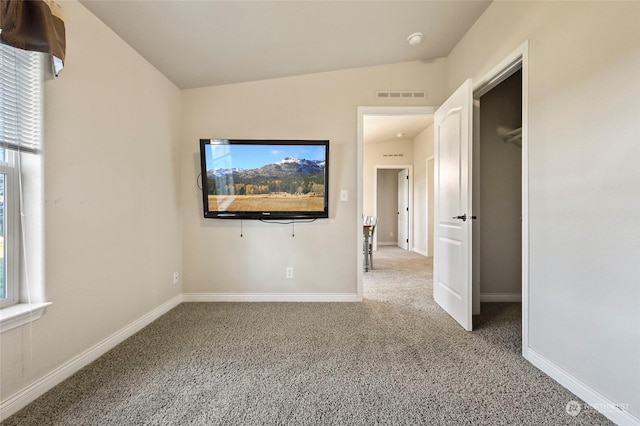 carpeted spare room with vaulted ceiling