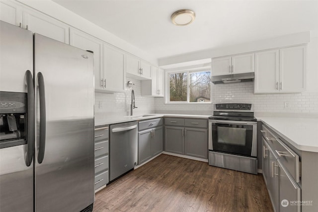 kitchen with gray cabinets, decorative backsplash, sink, stainless steel appliances, and dark hardwood / wood-style flooring