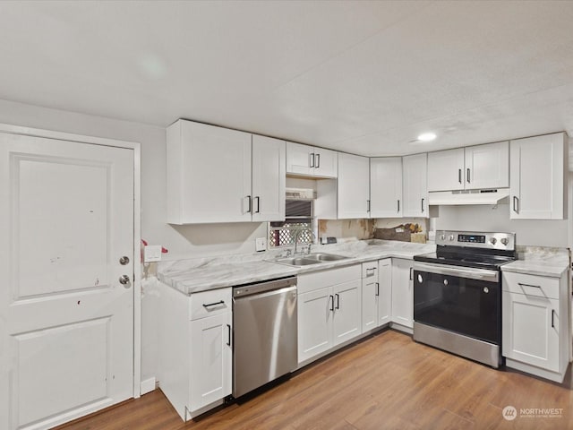 kitchen with sink, light wood-type flooring, appliances with stainless steel finishes, and white cabinetry