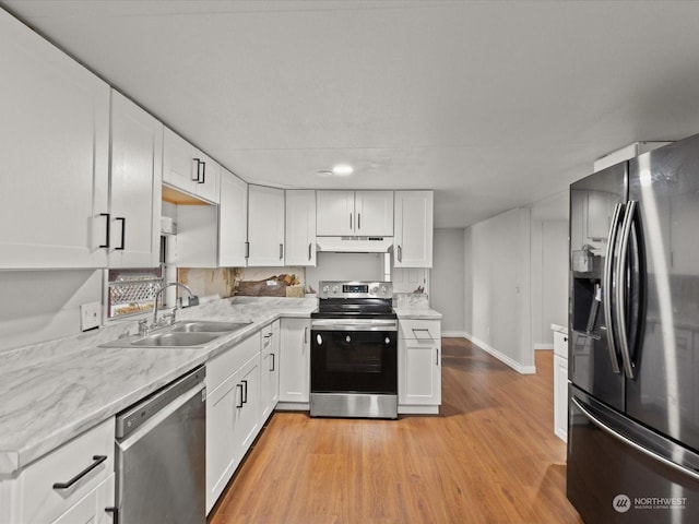 kitchen with light stone counters, stainless steel appliances, light hardwood / wood-style floors, white cabinetry, and sink