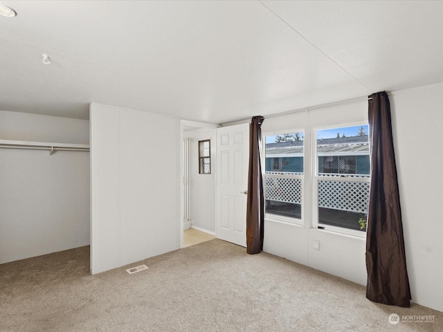 unfurnished bedroom with a closet and light carpet