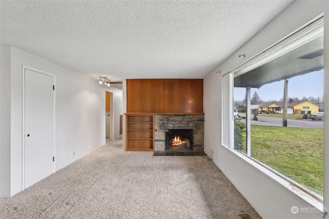 unfurnished living room with a textured ceiling, built in features, carpet flooring, and a fireplace