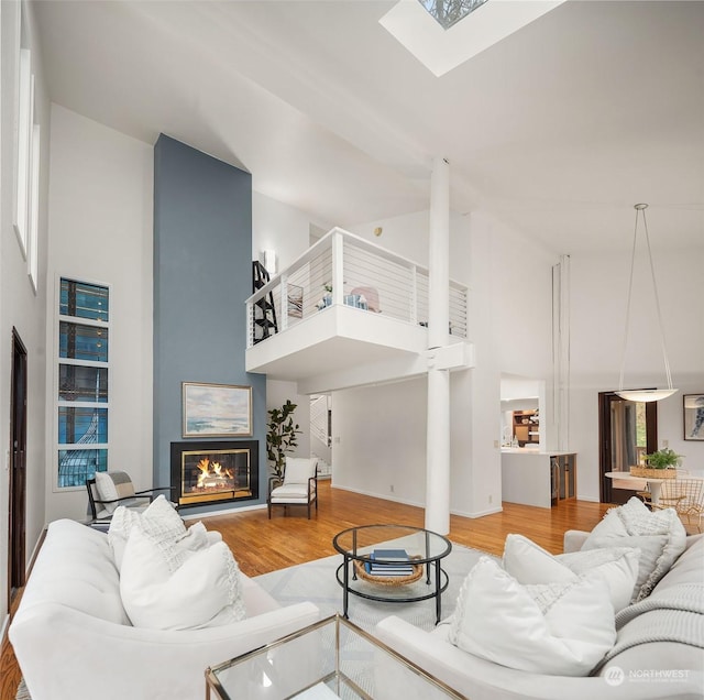 living room featuring a skylight, a towering ceiling, and wood-type flooring