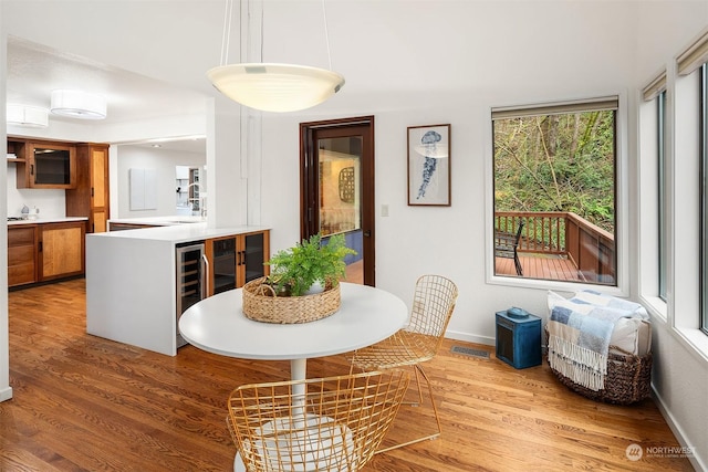 dining space with beverage cooler, wood-type flooring, and sink