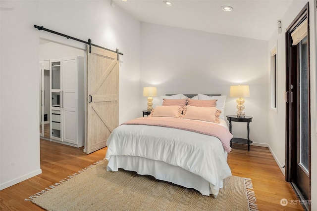 bedroom with a barn door and light wood-type flooring