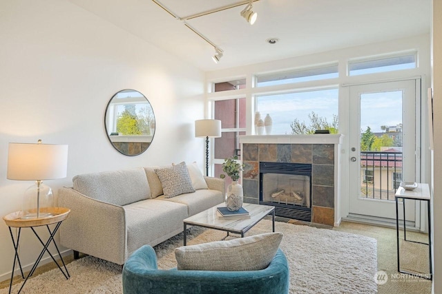 living room featuring a tiled fireplace, a healthy amount of sunlight, and vaulted ceiling