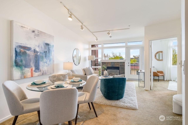 dining space with light carpet and a fireplace