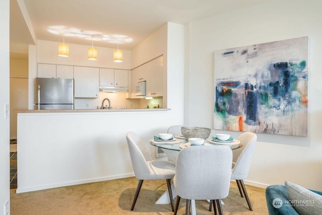 dining area with sink and light colored carpet