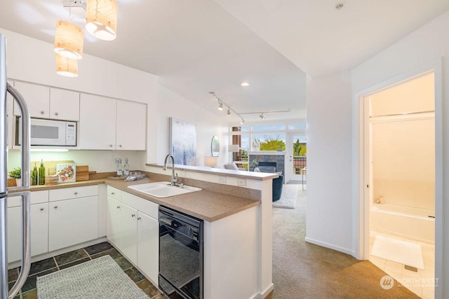 kitchen featuring kitchen peninsula, white microwave, white cabinetry, black dishwasher, and sink