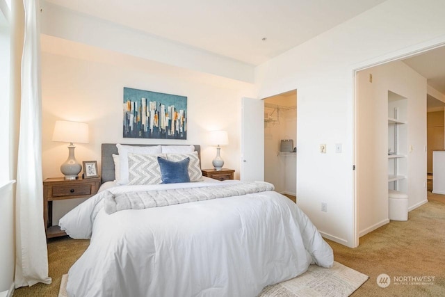 carpeted bedroom featuring a walk in closet and a closet