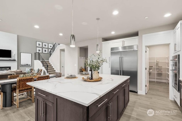 kitchen with white cabinetry, dark brown cabinets, hanging light fixtures, and appliances with stainless steel finishes