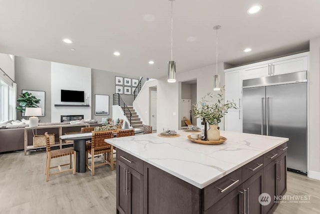 kitchen featuring stainless steel built in fridge, decorative light fixtures, white cabinets, light hardwood / wood-style flooring, and dark brown cabinets