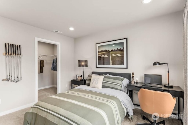 bedroom featuring a walk in closet, a closet, and light carpet