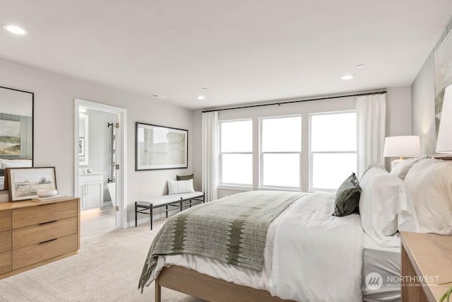 carpeted bedroom featuring multiple windows and ensuite bath