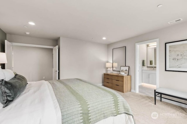 bedroom with ensuite bathroom and light colored carpet