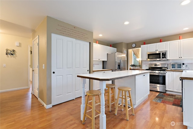 kitchen featuring a breakfast bar area, tasteful backsplash, a kitchen island, stainless steel appliances, and white cabinets