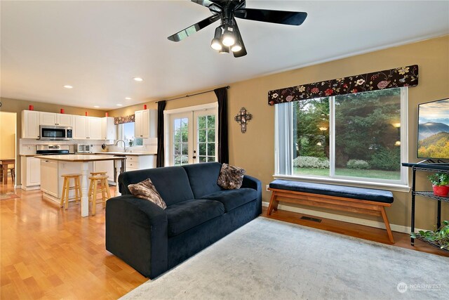 living room with ceiling fan, sink, light wood-type flooring, and french doors