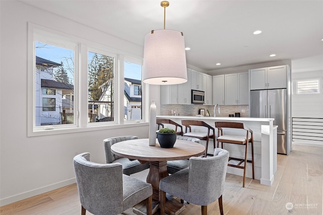 dining space with sink and light wood-type flooring