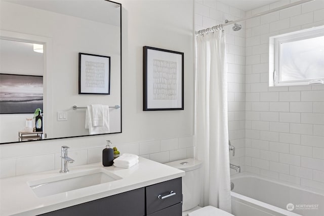 full bathroom featuring tile walls, toilet, vanity, and shower / bath combo