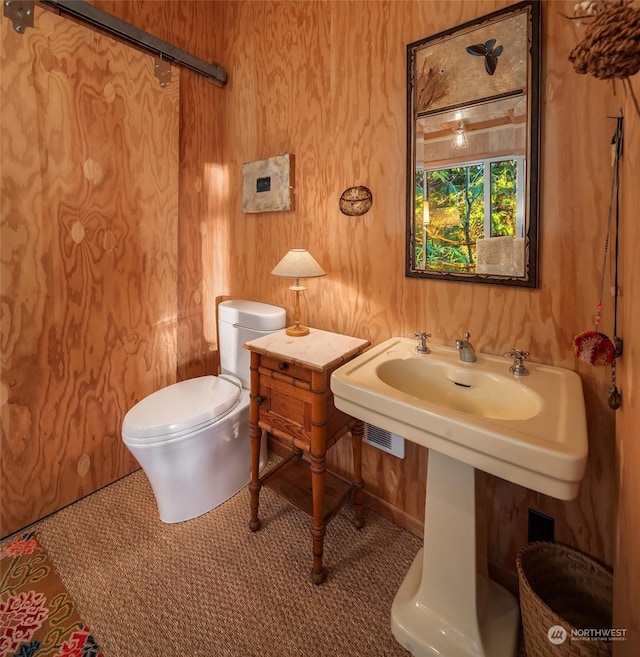 bathroom featuring toilet and wood walls