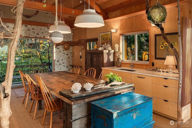 dining room with sink, wood walls, and beam ceiling