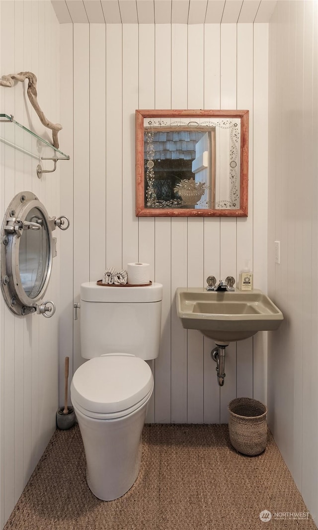 bathroom with toilet and wooden walls