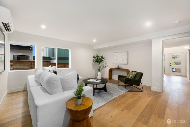 living room with a wall mounted AC and light hardwood / wood-style flooring