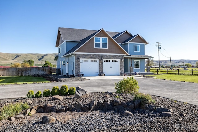 craftsman inspired home with a mountain view, central AC, a front yard, and a garage