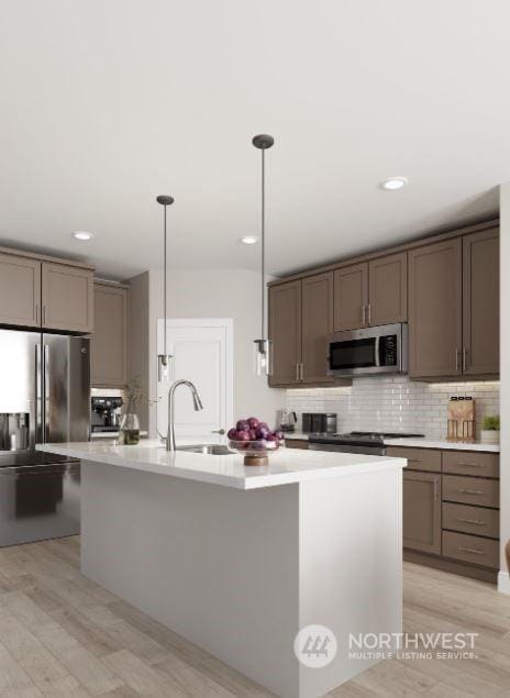 kitchen featuring sink, stainless steel appliances, a kitchen island with sink, and pendant lighting