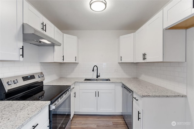 kitchen featuring stainless steel appliances, light stone counters, sink, white cabinetry, and backsplash