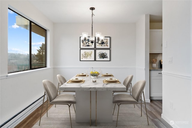 dining room featuring a healthy amount of sunlight, light wood-type flooring, a baseboard radiator, and a chandelier