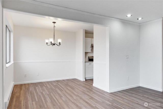 empty room featuring baseboard heating, a chandelier, crown molding, and light hardwood / wood-style flooring