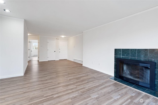 unfurnished living room featuring a tiled fireplace, baseboard heating, light hardwood / wood-style floors, and crown molding