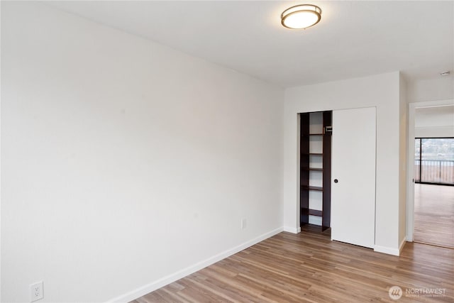 unfurnished bedroom with baseboards, light wood-style floors, and a closet