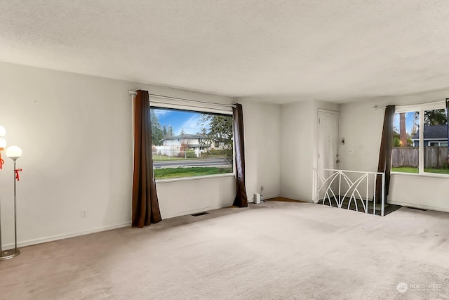 carpeted spare room with a textured ceiling