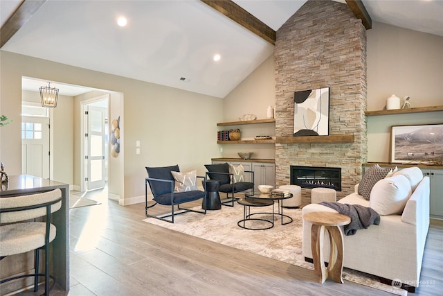 living room featuring light wood-type flooring, a stone fireplace, and lofted ceiling with beams