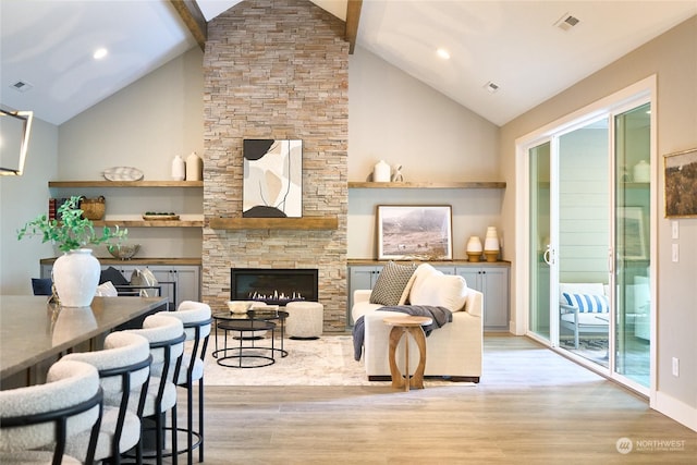 living room featuring a fireplace, light hardwood / wood-style floors, and lofted ceiling with beams