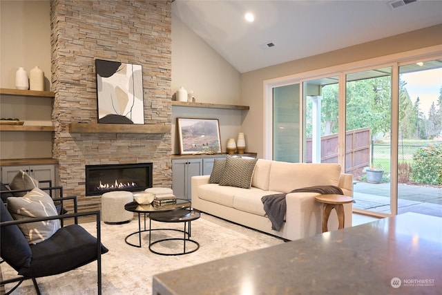 living room with lofted ceiling and a stone fireplace