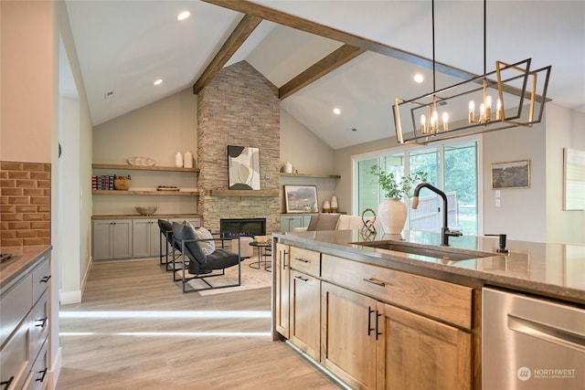 kitchen with beamed ceiling, pendant lighting, a fireplace, sink, and stainless steel dishwasher