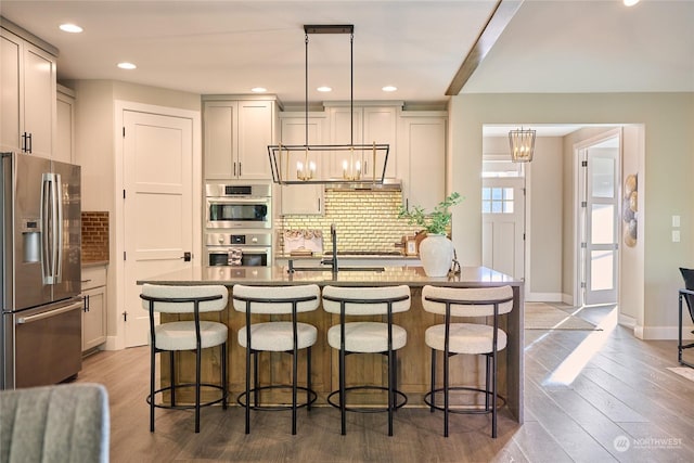 kitchen featuring a breakfast bar, decorative light fixtures, tasteful backsplash, and appliances with stainless steel finishes