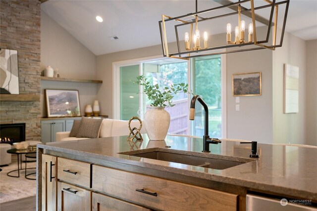 kitchen with dishwasher, pendant lighting, stone countertops, a fireplace, and sink