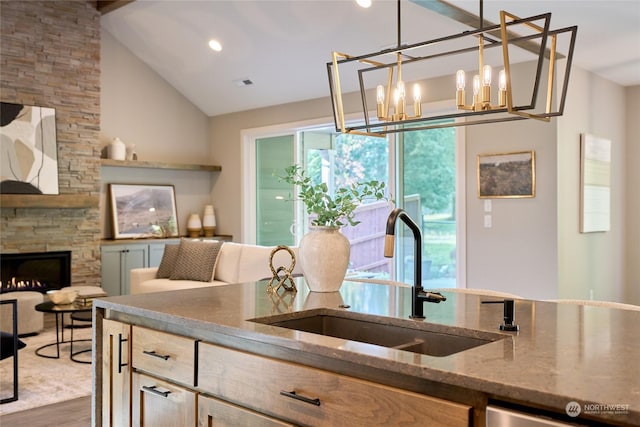 kitchen with an inviting chandelier, dark hardwood / wood-style flooring, a fireplace, sink, and stone countertops