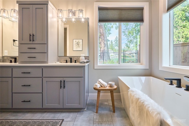 bathroom featuring decorative backsplash, vanity, a tub to relax in, and plenty of natural light