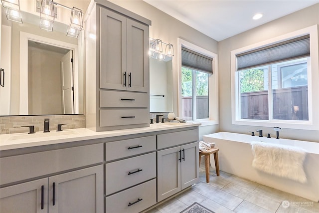 bathroom featuring vanity, tile patterned flooring, backsplash, and a bath