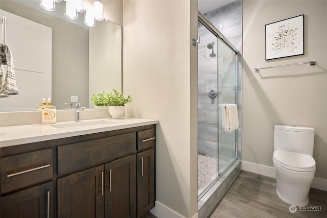 bathroom featuring toilet, wood-type flooring, walk in shower, and vanity