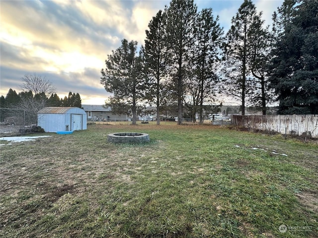 yard at dusk with a fire pit and a shed