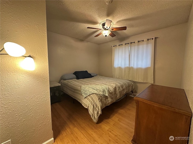 bedroom with hardwood / wood-style floors, a textured ceiling, and ceiling fan