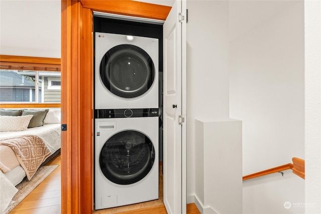 laundry room with light wood-type flooring and stacked washer / dryer