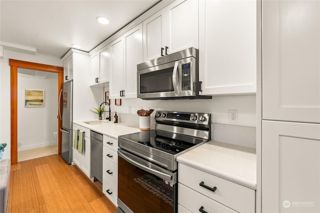 kitchen featuring stainless steel appliances, white cabinetry, sink, and light hardwood / wood-style flooring