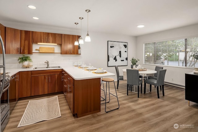 kitchen featuring hanging light fixtures, a baseboard radiator, a kitchen breakfast bar, sink, and kitchen peninsula